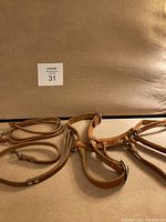 Light brown leather chest harness lying flat, showing various adjustable straps and metal rivets