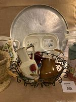 Wide view of mortar, pestle, kitchenware items arranged with metal pizza pan in background and children dishes visible