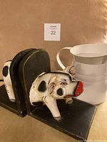 Pig bookends and white water pitcher shown together on brown background