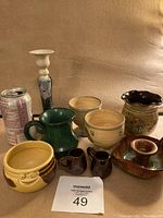 Photo showing full collection of pottery items with soda can for size reference.