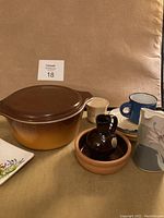 Photo showing the brown gradient Pyrex casserole bowl with lid, small pottery pieces including Noritake jug, stack of plates, and various ceramic dishes