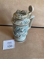 Full front view of the ceramic stein showing detailed reliefs and sculpted racing car on lid.