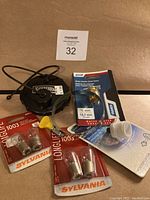 Lot of RV maintenance parts including black water tank cap, water heater drain valve, winterized plug, and Sylvania Longlife 1003 lightbulb packs.