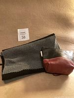 Infinity scarf with black and gray stripes laid flat next to the two-tone leather wrist wallet on a beige background.