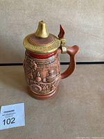 Front side of the Avon collectible fireman tribute beer stein showing detailed scenes of firefighting equipment and the lid.