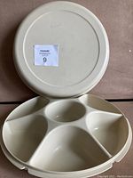 Top view of the closed vintage Tupperware round compartment tray showing the lid with a MaxSold sticker on top.
