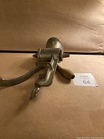 Side angle showing the entire meat grinder with crank handle and clamp base.