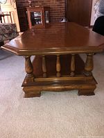 Side view showing the spindle-style wooden supports and the solid craftsmanship of the coffee table.