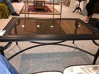View of the rectangular smoked glass top with a black metal frame on carpet.