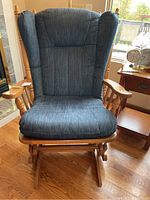 Front view of wooden glider rocker chair with blue cushioned seat and backrest, showing overall clean condition.