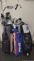 Photo of three golf bags standing upright containing assorted golf clubs and accessories, showing full lot contents