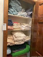 Shelves of assorted linens in linen closet including sheets, pillowcases, and blankets folded and stacked.