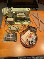 Front view of Singer 319W sewing machine with accessories including pedal, discs, feet, and notions.