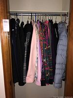 Photo of over twenty women's outerwear jackets and coats hanging on a rod in a closet.