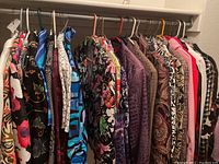 Photo showing a rack of assorted women's jackets and tops in various colors and patterns hanging on hangers.