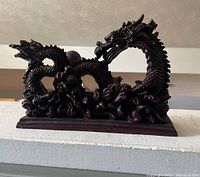 Side view of the dark cherry wood dragon sculpture with detailed carving on grain and scales.