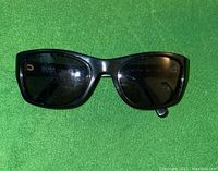 Black Hugo Boss sunglasses front view showing rectangular dark lenses and frame on green background.