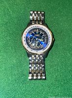 Front view of Paul Hardin wristwatch showing dark multi-function dial with silver and gold tone stainless steel band on green background.