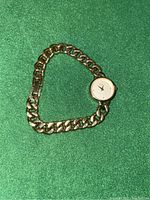 Gold-tone women's Timex watch with chain link band laid on green fabric, showing light scratches on dial and band.