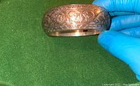Side view of silver bracelet showing detailed engraved patterns and slight tarnishing.