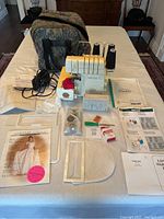 Full lot overview on table showing serger, case, cones, accessories, manuals