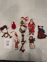 Top view of all nine Christmas ornaments arranged on a white cloth background, showing diverse styles including Santa figures, cats, and snowmen.
