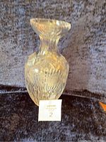 Front view of clear glass crystal vase with deep cut etched floral and geometric design on a dark fabric background.