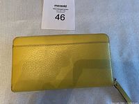 Yellow Kate Spade leather wallet laid flat, front view.