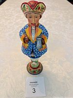 Front view of the nutcracker figurine on a table showing the detailed painted face, hat, and clothing.