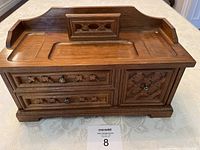 Front view of men's wooden jewelry chest showing three drawers with carved detail and metal knobs.