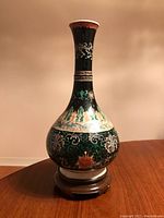 Full view of porcelain vase on wood stand against plain background