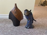 Both Asian-style figurines displayed on carpeted floor showing size and contrast