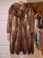 Full view of ladies fur coat hanging on hanger showing front, collar, buttons, and full length.