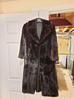 Full view of dark brown mink fur coat on hanger
