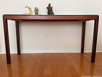 Front view of rosewood hall table against wall with decorative items on top