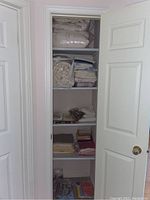 Closet with multiple shelves filled with folded linens