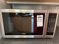 Front view of the Whirlpool microwave oven showing stainless steel finish and display with control panel.