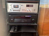 Full view of NEC cassette deck and Sony receiver stacked in shelf with two remotes.