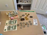 Full lot overview on table showing coins, bills, and belt buckle.