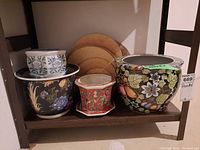 Overview of four ceramic planters on shelf with three cork trivets behind