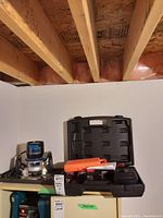 Craftsman electronic router in silver and black with a blue label, cordless drill case closed next to it