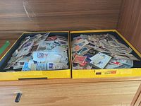 Two yellow boxes filled with assorted stamps and envelopes on a wooden surface.