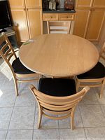 Top-down view of maple wood round table and four matching chairs in a tiled room