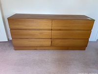 Front view of teak dresser showing six drawers and recessed handles