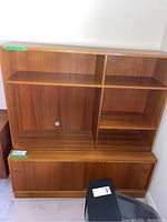 Front view of teak veneer cabinet in two pieces, showing open upper shelving and lower sliding-door cabinet