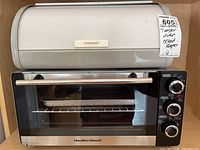 Hamilton Beach toaster oven and metal bread box on shelf, front view