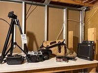 Overall shot showing tripod, cameras, flash, range finder, and bag on shelf