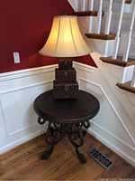 Full view of round accent table with wood lamp placed on it near staircase showing the overall size and style.