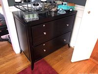 Front and side view of the black stained wooden filing cabinet showing two drawers with metal knobs and lock key slots.