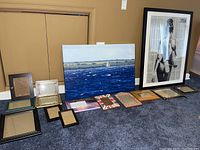 Overview of lot showing two framed art pieces and ten empty frames on carpet